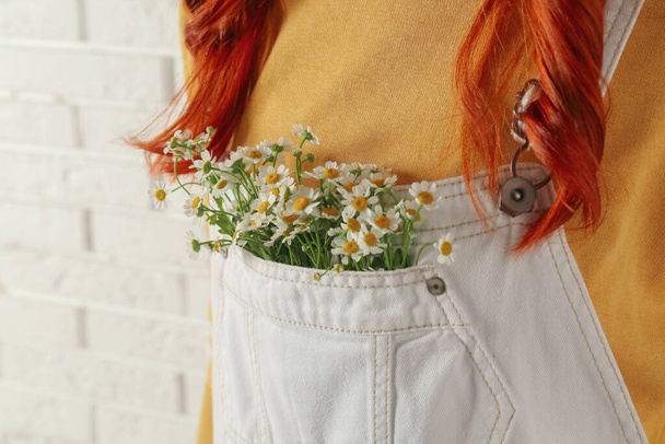 Woman with beautiful tender chamomile flowers in white jumpsuit's pocket, closeup - Fotoğraf, Görsel