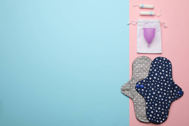 Reusable cloth pads, menstrual cup and disposable tampons on color background, flat lay. Space for text - 写真・画像
