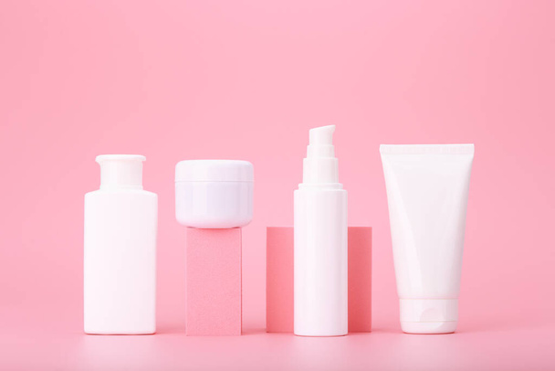 Trendy composition in pink colors with set of cosmetic bottles with beauty products on geometric props against bright pink background. Concept of anti acne or regular basic skin treatment - Foto, Imagem
