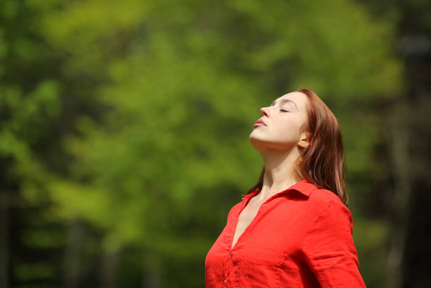 Relaxed woman in red breathing fresh air standing in a forest - Foto, Imagem