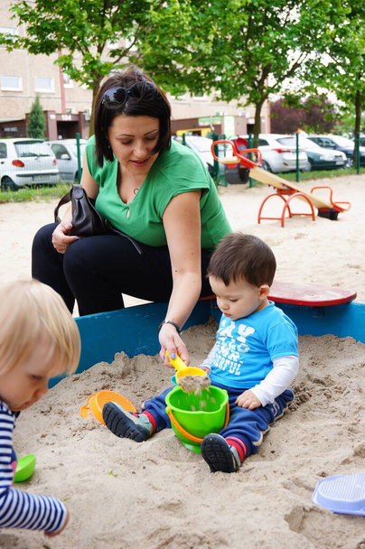 POZNAN, POLAND - May 19, 2015: The mother playing with her son in a sandpit at a playground - Photo, image