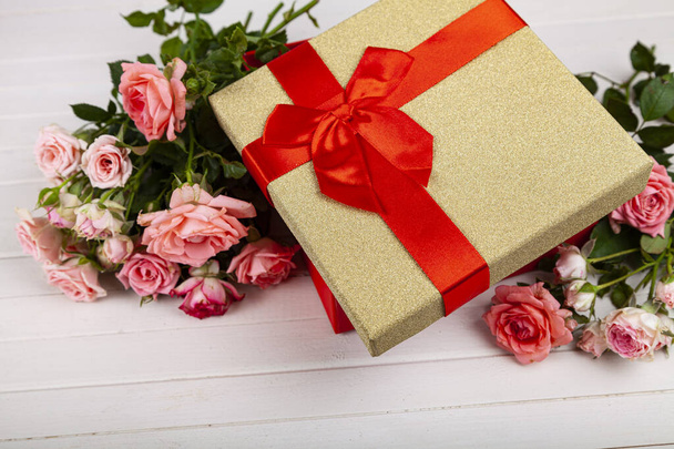 Bouquet of pink roses in a red box on a wooden background. Greeting card with flowers. - Photo, image