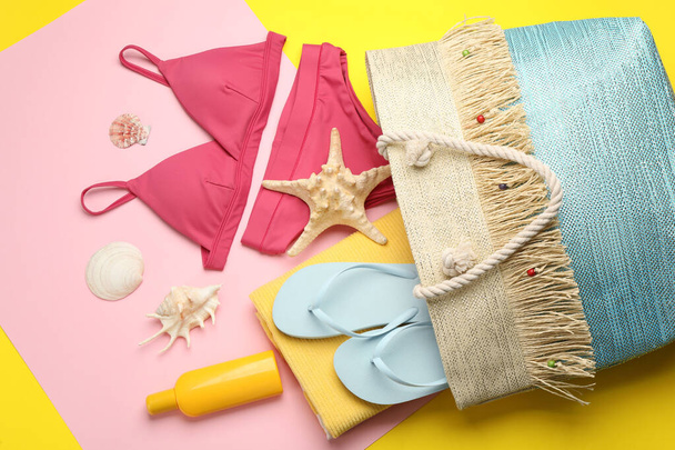 Stylish bag with beach accessories on color background, flat lay - 写真・画像