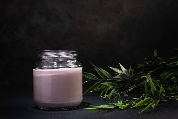A closeup of a jar of yogurt on dark background. - Фото, зображення