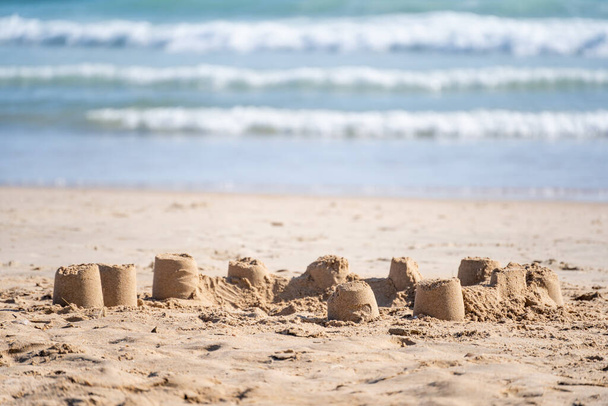 The small sand castles on the sandy beach on the coast - Foto, Imagen