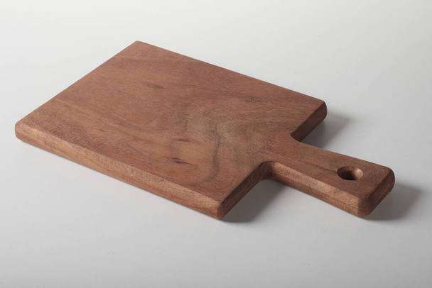 A brown wooden kitchen hot dish trivet or a chopping board with a handle on white background - Foto, Bild