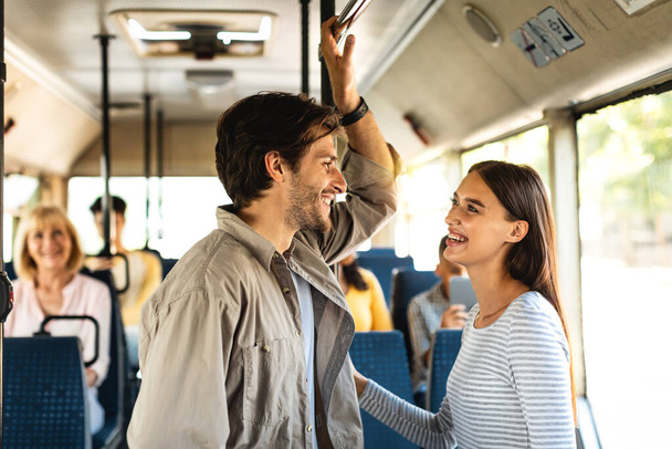 Hermosa pareja sonriente de pie en el autobús y hablando - Foto, imagen