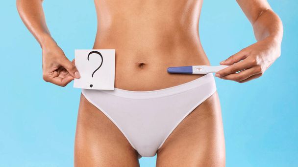 Γυναίκα που κατέχει τεστ εγκυμοσύνης και κάρτα με ερωτηματικό - Φωτογραφία, εικόνα