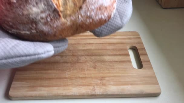 Μπέικερ βάζει φρεσκοψημένο ψωμί προζύμης σε ξύλινη σανίδα. - Πλάνα, βίντεο