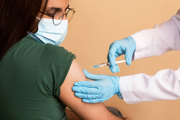 Enfermeira fazendo injeção intramuscualr para homem árabe na clínica, close-up - Foto, Imagem