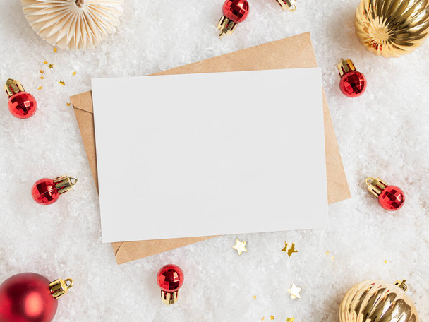 Puste białe pocztówki i koperty rzemieślnicze i różne dekoracje świąteczne na sztucznym tle śniegu Wakacje i zaproszenie makieta. Boże Narodzenie lub Nowy Rok życzenia układ. Odbiór. Widok z góry - Zdjęcie, obraz