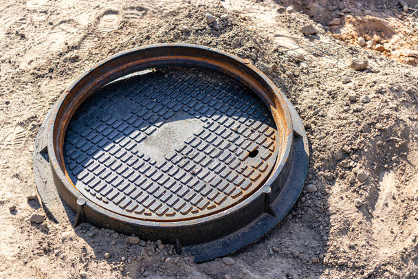 A cast-iron sewer manhole prepared for installation. Close-up. Road works. Shelter for underground utilities - Photo, Image