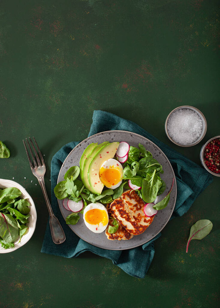 Sağlıklı keto paleo diyeti kahvaltısı: haşlanmış yumurta, avokado, halloumi peyniri, salata yaprakları. - Fotoğraf, Görsel