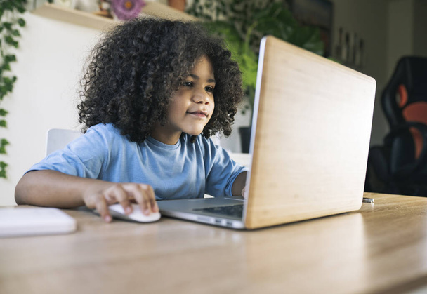 kleiner Afro-Junge, macht Hausaufgaben zu Hause mit dem Computer, zurück in die Schule, Hausaufgabenbetreuung - Foto, Bild