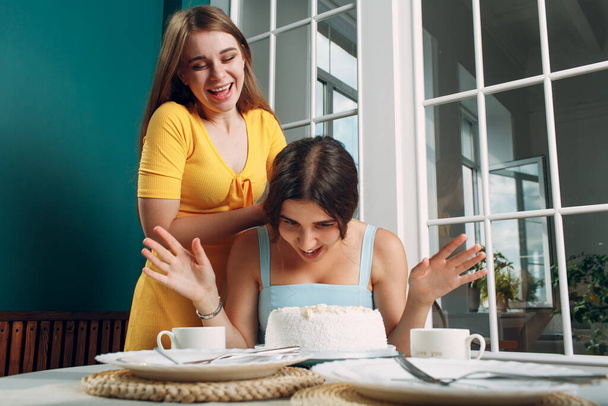 Jonge vrouw dompelt gezicht in witte taart met room. Gelukkige verjaardag concept. - Foto, afbeelding