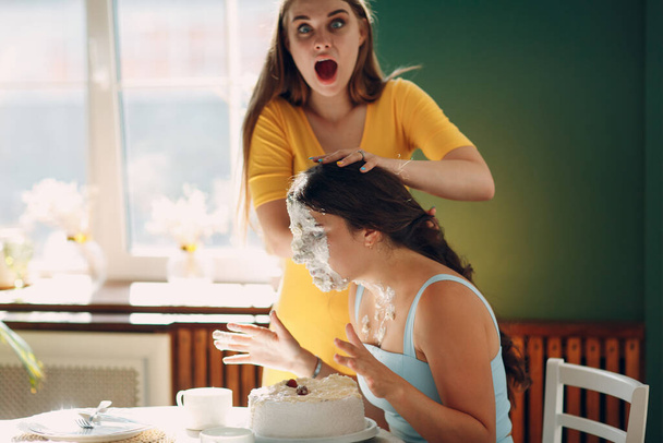 Jeune femme plonge le visage dans un gâteau blanc avec de la crème. Joyeux anniversaire concept. - Photo, image