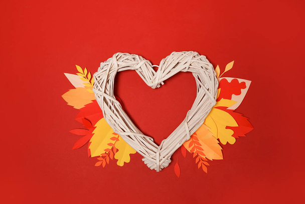Autumn heart symbol with orange falling leaves on red background - Photo, Image