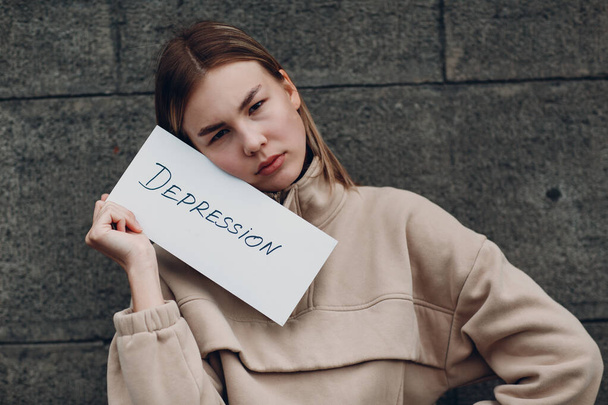 Mujer sostiene en hoja de papel con la palabra Depresión
 - Foto, Imagen