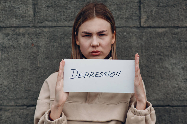 Γυναίκα κρατά στο χέρι φύλλο χαρτιού με τη λέξη κατάθλιψη - Φωτογραφία, εικόνα