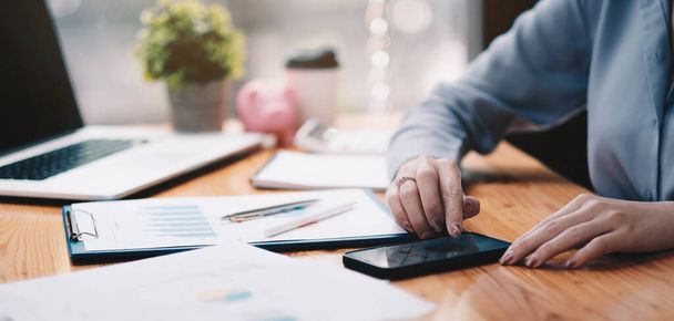 üzleti dokumentumok az irodai asztalon okostelefonnal és grafikonnal pénzügyi diagram és az irodai dolgozó üzletemberek - Fotó, kép