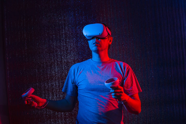 Young caucasian man 25-30 years using virtual reality headset. VR, future, gadgets, technology concept in neon light. - Photo, Image