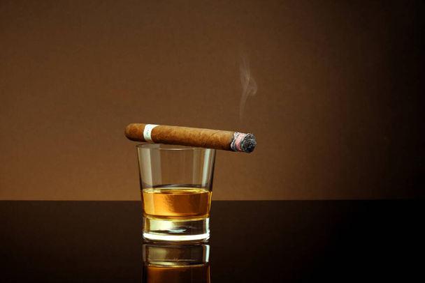 Closed up view of glass of whiskey with cigar on top on color back - Φωτογραφία, εικόνα