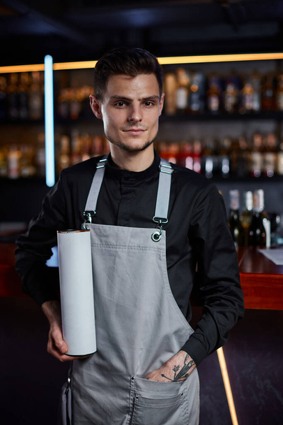 Handsome barman in apron standing at the bar counter - Photo, Image
