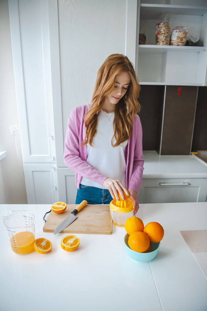 Fruit juice. Woman squeeze fresh juice. Ginger person with freckles working in kitchen. - Foto, imagen