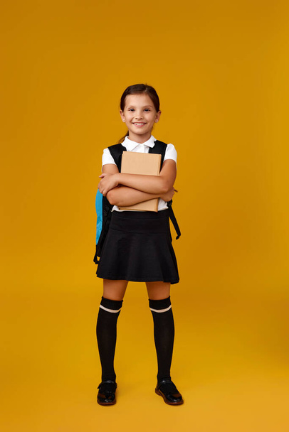 cute schoolgirl with backpack and book full length. - Фото, зображення