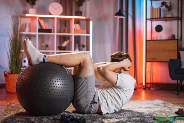 Middle aged man using fitball for doing abs workout on floor - Foto, Imagen