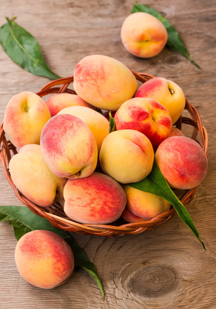 Спелые персики в плетеной корзине   - Фото, изображение