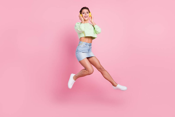 Full size profilo lato foto di giovane ragazza felice sorriso positivo auricolari saltare isolato su sfondo colore pastello - Foto, immagini