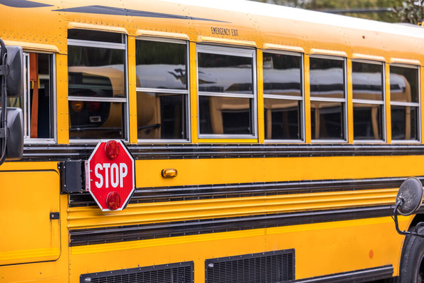 Zbliżenie żółtego pomarańczowego autobusu szkolnego z czerwonym znakiem stopu na powrót do szkoły - Zdjęcie, obraz