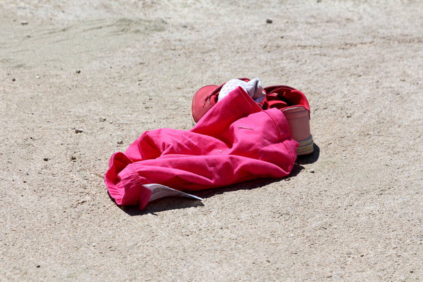 Розовая женщина боксерские шорты рядом с розовыми и белыми женщинами бег обувь заполнена подержанные носки, оставленные на местном пляже в то время как девушка пошла плавать в теплый солнечный весенний день - Фото, изображение