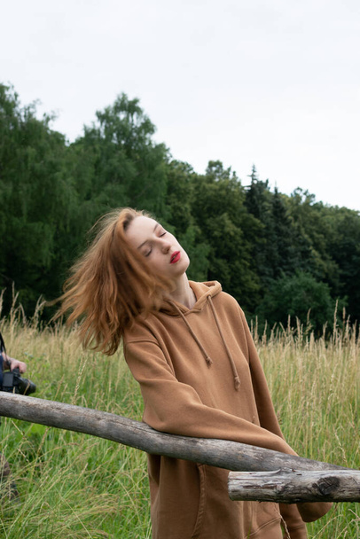 молодая красивая женщина позирует летом в поле в коричневом свитере - Фото, изображение