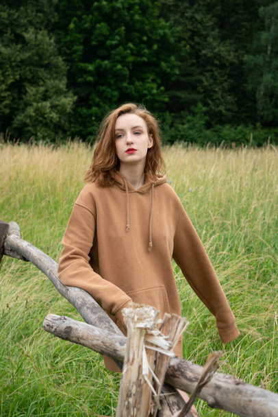 nuori kaunis nainen poseeraa kesällä pellolla ruskea pusero - Valokuva, kuva