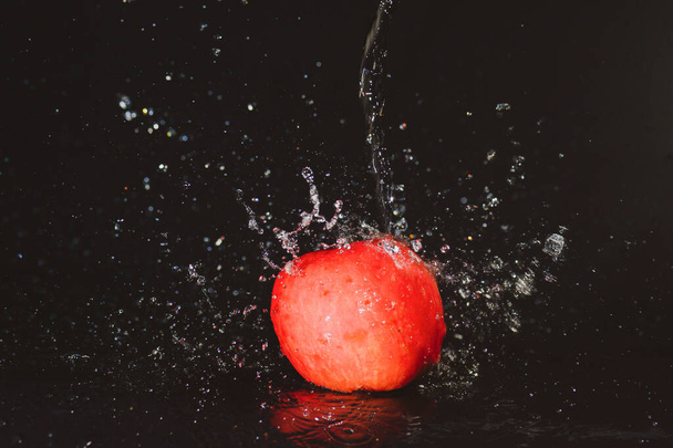 Mele rosse in spruzzi d'acqua su sfondo nero. Acqua di mela spruzzata su sfondo nero - Foto, immagini