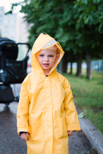 Portrait of a little boy in a yellow raincoat. - Fotó, kép