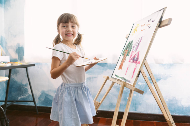 Evde fırça tutan ve tuvale resim çizen sevimli küçük bir kızın portresi. Erken çocukluk eğitimi, resim, yetenek, güven Pozitifliği Özgürlük Yaratıcı Kavram. - Fotoğraf, Görsel