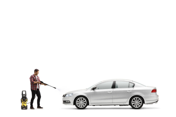 Full length shot of a man washing a silver car with a pressure washer machine isolated on white background - Foto, Imagen