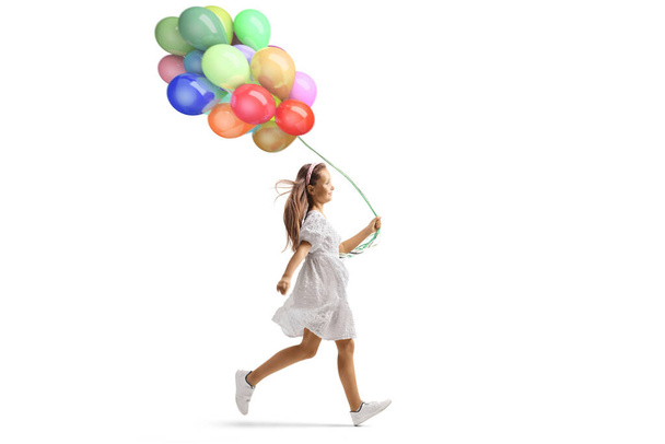 Girl in white dress running and holding a bunch of balloons isolated on white background - Foto, afbeelding