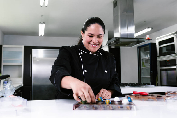 Латин - жінка - шеф-кондитер у чорній уніформі при приготуванні смачних цукерок на кухні в Мексиці (Мексика). - Фото, зображення