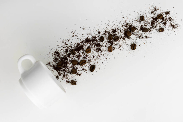мелена кава і кавові зерна, що виливаються з чашки на сірому фоні
. - Фото, зображення