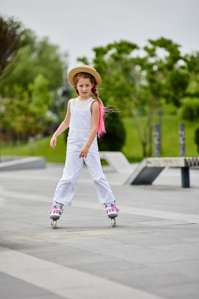 Cute little child girl on roller skates at park - Φωτογραφία, εικόνα