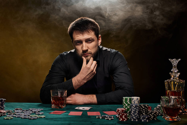Bearded casino player man playing poker on green table - Foto, imagen