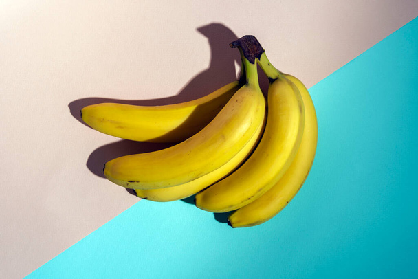 yellow bananas on a pink and turquoise background, pattern, minimalism, healthy food. - Fotografie, Obrázek