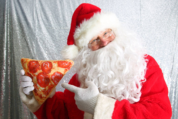 Santa Claus. Santa Enjoys a Slice of Pizza. Santa Loves Pizza. Food and Drink. - Photo, image