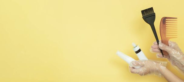 Кисті і трубки для фарбування волосся в рукавичках на жовтому тлі з копіювальним простором
 - Фото, зображення