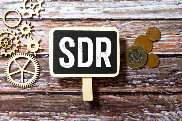 SDR Ειδικά Τραβηκτικά Δικαιώματα είναι το ακρωνύμιο πίσω από σκισμένο χαρτί γραφείου με αριθμούς. - Φωτογραφία, εικόνα