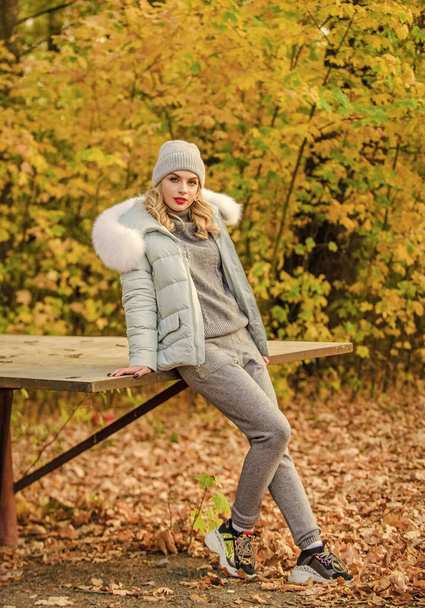 Fresh air and good mood. girl relax among fallen leaves. cosy sport suit. sporty girl with puffed jacket. wear comfort clothes. warm clothes for fall season. woman in hat enjoy autumn. walk in park - Photo, image
